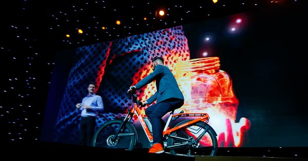 electric bike onto the stage, tricked out in Magento orange with #RoadToImagine and the Magento logo