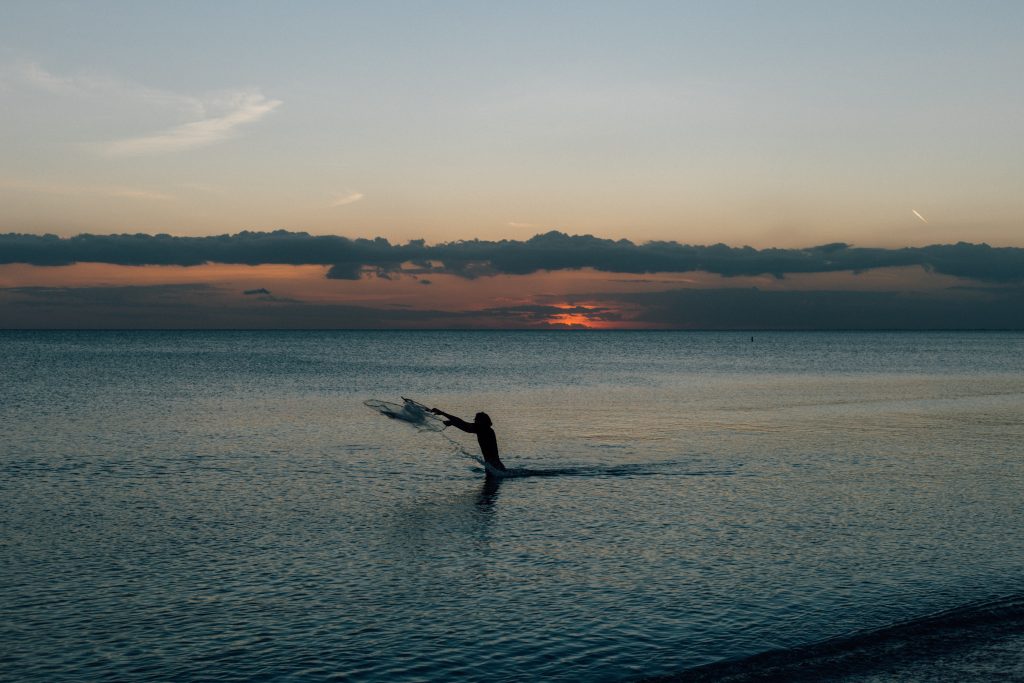 man standing in water fishing with net